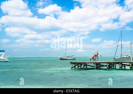 Jeune couple practicing yoga on pier, San Pedro, Belize Banque D'Images