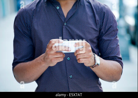 Cropped shot of young man on city street using smartphone Banque D'Images