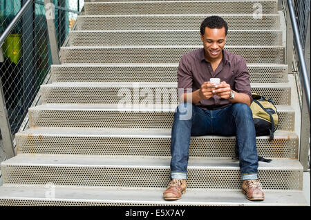 Young man texting on smartphone sur l'escalier de la ville Banque D'Images