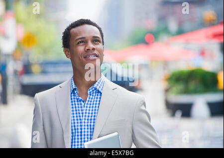 Young businessman walking on city street transportant tablette numérique Banque D'Images