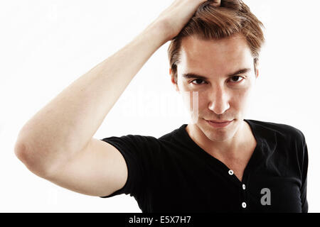 Studio portrait of young man with hand in hair Banque D'Images