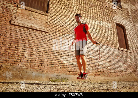 Jeune homme exerçant avec la corde à sauter sur wasteland Banque D'Images