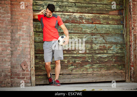 Young male soccer player chatting on smartphone Banque D'Images