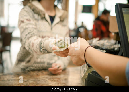 Female customer handing paiement au comptoir café sur serveur Banque D'Images