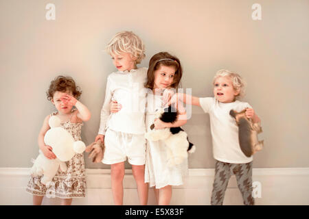 Portrait de quatre jeunes enfants dans une rangée, un pleurer Banque D'Images