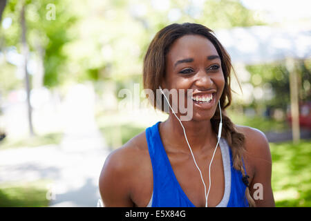 Jeune coureuse wearing earphones in park Banque D'Images