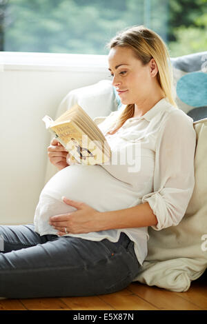 Pregnant woman reading book Banque D'Images