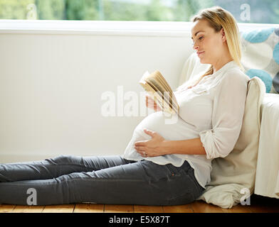 Pregnant woman reading book Banque D'Images