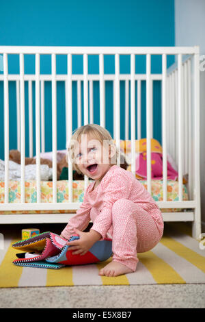 Female toddler jouant avec livre photo textile dans la chambre Banque D'Images