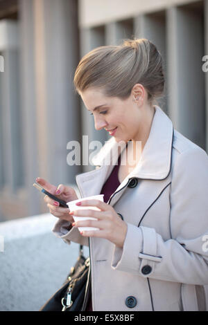 Young businesswoman texting on smartphone in city Banque D'Images