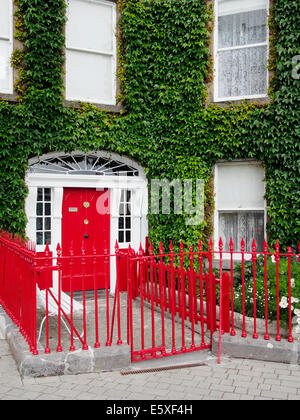 Georgian House sur l'octogone, la ville de Westport, Comté de Mayo, Connaught, République d'Irlande avec rouge vif et porte en fer forgé. Banque D'Images