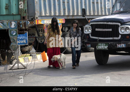 Lahore. 7e août, 2014. Les femmes pakistanaises traverser une route comme camions porte-conteneurs sont placés pour bloquer la zone près de la maison de l'érudit religieux Tahir-ul-Qadri, avant les prochains rallye anti-gouvernement du Pakistan Tehreek Awami (PAT) dans l'est de Lahore au Pakistan le 7 août 2014. Tahir-ul-Qadri, a lancé la campagne contre Nawaz Sharif et a laissé entendre à rejoindre Khan en mars. La menace d'une manifestation nationale par le Tehrik-e-Insaf dirigé par cricketer-devenu politicien Imran Khan a mis la pression sur le gouvernement du Premier Ministre pakistanais Nawaz Sharif. Credit : Jamil Ahmed/Xinhua/Alamy Live News Banque D'Images