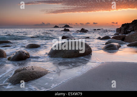 Rochers arrondis couverts patelle au coucher du soleil sur une plage déserte à Porth Nanven Cove également connu sous le nom de lit bébé Vallée, près de Land's End dans Banque D'Images