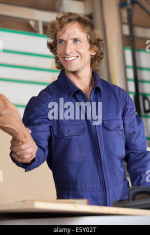 Heureux carpenter shaking hands with collègue Banque D'Images