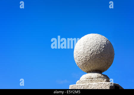 Balle en pierre contre le ciel bleu sur socle Banque D'Images