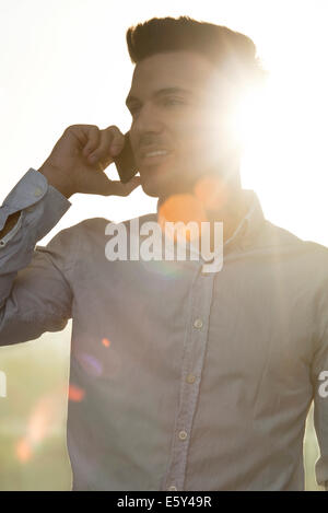 Young man talking on cell phone, silhouette Banque D'Images