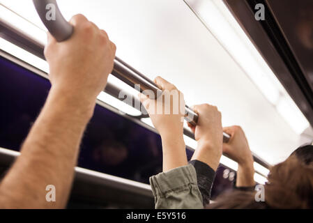 Communters on subway holding poignée de maintien, close-up Banque D'Images