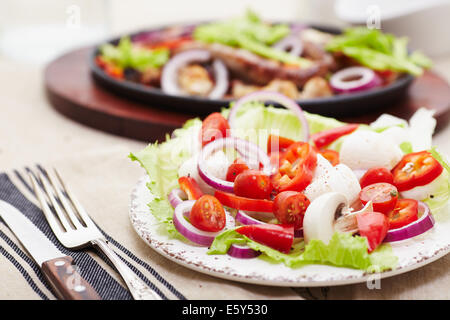 Dés de poulet cuit et saucisse avec oignons, poivrons, mushrrooms et une salade de tomates, champignons, poivrons et la laitue. Banque D'Images