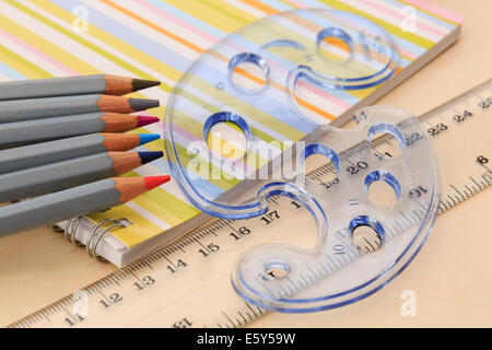 Matériel éducatif pour l'ordinateur portable de dessin, crayons de couleur, règle et formes géométriques stencil sur un bureau. Angleterre Royaume-uni Grande-Bretagne Banque D'Images