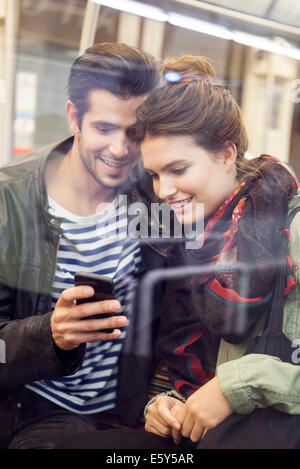 Jeune couple riding subway looking at digital tablet together Banque D'Images