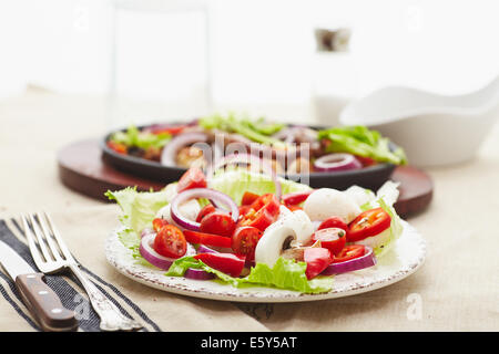 Dés de poulet cuit et saucisse avec oignons, poivrons, mushrrooms et une salade de tomates, champignons, poivrons et la laitue. Banque D'Images