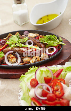 Dés de poulet cuit et saucisse avec oignons, poivrons, mushrrooms et une salade de tomates, champignons, poivrons et la laitue. Banque D'Images