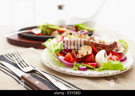 Dés de poulet cuit et saucisse avec oignons, poivrons, mushrrooms et une salade de tomates, champignons, poivrons et la laitue. Banque D'Images