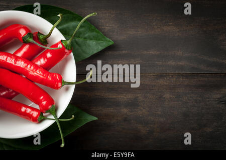Hot Chili Peppers sur plaque blanche sur fond de table en bois avec l'exemplaire de l'espace. Vue d'en haut Banque D'Images