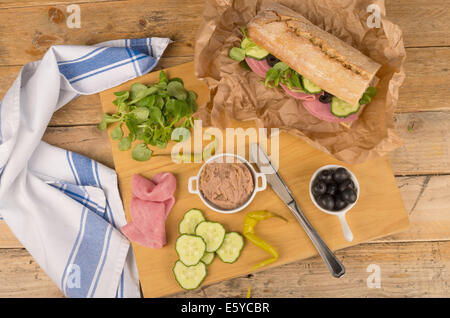 Baguette méditerranéen avec des ingrédients sur planche à découper en bois Banque D'Images