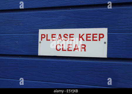 Veuillez rester à l'écart panneau d'avertissement en rouge sur un fond blanc sur une porte bleue Banque D'Images