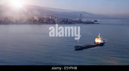 Un cargo flottant sur l'eau face à une baie au lever du soleil, au Liban. Banque D'Images