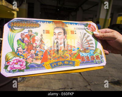 Bangkok, Thaïlande. 10e Août, 2014. Un homme tient une pile de l'enfer de l'argent avant de jeter dans un baril de brûlage à Bangkok pour Ghost Month. L'enfer de l'argent est une forme de joss le papier imprimé pour ressembler à cours légal des billets de banque et est utilisé dans des cérémonies religieuses dans les communautés chinoises. Le septième mois de l'année lunaire chinoise est appelée ''Ghost'' mois pendant lequel les fantômes et les esprits, y compris ceux de l'ancêtres décédés, sortent de la sphère inférieure. Il est courant pour les Chinois de faire mérite au cours du mois par la combustion de ''l'enfer de l'argent'' et la présentation de la nourriture pour les fantômes. (Crédit Imag Banque D'Images