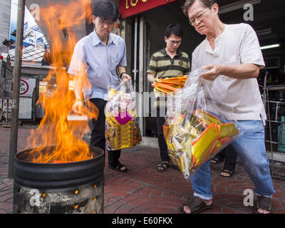 Bangkok, Thaïlande. 10e Août, 2014. Les hommes pour ''papier'' en joss un baril de brûlage sur le premier jour de mois Ghost à Bangkok. Joss paper également connu sous le nom de l'argent fantôme, sont des feuilles de papier et/ou sur support papier, l'artisanat dans l'holocauste. Le septième mois de l'année lunaire chinoise est appelée ''Ghost'' mois pendant lequel les fantômes et les esprits, y compris ceux de l'ancêtres décédés, sortent de la sphère inférieure. Il est courant pour les Chinois de faire mérite au cours du mois par la combustion de ''l'enfer de l'argent'' et la présentation de la nourriture pour les fantômes. Crédit : Jack Kurtz/ZUMA/Alamy Fil Live News Banque D'Images
