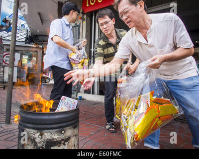 Bangkok, Thaïlande. 10e Août, 2014. Les hommes pour ''papier'' en joss un baril de brûlage sur le premier jour de mois Ghost à Bangkok. Joss paper également connu sous le nom de l'argent fantôme, sont des feuilles de papier et/ou sur support papier, l'artisanat dans l'holocauste. Le septième mois de l'année lunaire chinoise est appelée ''Ghost'' mois pendant lequel les fantômes et les esprits, y compris ceux de l'ancêtres décédés, sortent de la sphère inférieure. Il est courant pour les Chinois de faire mérite au cours du mois par la combustion de ''l'enfer de l'argent'' et la présentation de la nourriture pour les fantômes. Crédit : Jack Kurtz/ZUMA/Alamy Fil Live News Banque D'Images