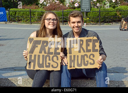 Portrait of a young man & woman holding panneau disant FREE HUGS. Dans la région de Union Square Park, New York City. Banque D'Images