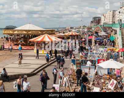 Une foule de vacanciers jolly profitez d'une promenade le long du front de mer de Brighton et de la promenade avec fête foraine attractions et boutiques de souvenirs Banque D'Images