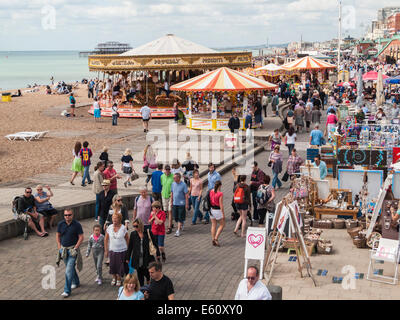 Une foule de vacanciers jolly profitez d'une promenade le long du front de mer de Brighton et de la promenade avec fête foraine attractions et boutiques de souvenirs Banque D'Images