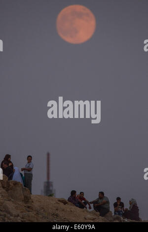 Le Caire, Égypte. 10e Août, 2014. Les Egyptiens parlent au sommet d'une colline de savoir quand l'upermoon' augmente au Caire, Égypte, le 10 août 2014. Le upermoon» «, techniquement connu sous le nom de 'lune périgée," s'affiche lorsque la lune est à son plus proche de la Terre dans son orbite, en faisant en sorte qu'il semble beaucoup plus grand et plus lumineux que d'habitude. Source : Xinhua/Chaoyue Pan/Alamy Live News Banque D'Images