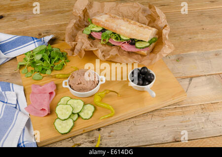 Baguette méditerranéen avec des ingrédients sur planche à découper en bois Banque D'Images