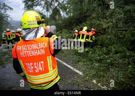 Bad Schwalbach, Allemagne. 10e Août, 2014. Les pompiers travaillent à l'élimination des arbres tombés dans les rues près de Bad Schwalbach, Allemagne, 10 août 2014. Une tornade avec une tempête de pluie a causé des dommages dans les millions dans le centre de bien-être. De nombreux véhicules ont été endommagés, toits de maisons et détruit les zones forestières. Photo : Boris Roessler/dpa/Alamy Live News Banque D'Images