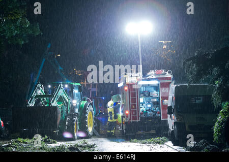 Bad Schwalbach, Allemagne. 10e Août, 2014. Les pompiers travaillent à l'élimination des arbres tombés dans les rues de Bad Schwalbach, Allemagne, 10 août 2014. Une tornade avec une tempête de pluie a causé des dommages dans les millions dans le centre de bien-être. De nombreux véhicules ont été endommagés, toits de maisons et détruit les zones forestières. Photo : Boris Roessler/dpa/Alamy Live News Banque D'Images