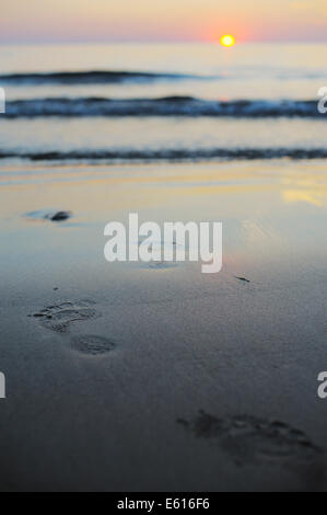 Les traces de pas qui mènent à la mer au coucher du soleil, le Pays de Galles, Royaume-Uni. Banque D'Images
