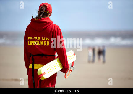 Un RLSS ou Royal Life Saving life guard monte la garde près de la mer sur une plage. Les gardiens de la vie aident à prévenir la noyade dans l'eau. Banque D'Images