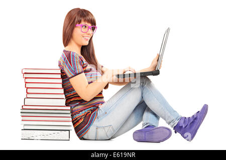 Femme étudie sur un ordinateur portable et s'appuyant sur une pile de livres Banque D'Images