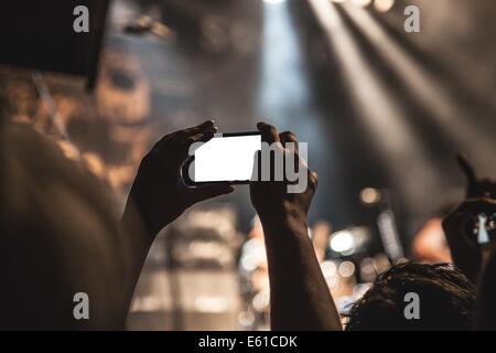 Un public lors d'un concert utilise des smartphones pour prendre des photos et filmer la performance. Cette tendance met en évidence l'utilisation croissante d'appareils mobiles pour capturer des événements en direct et partager des expériences. Banque D'Images