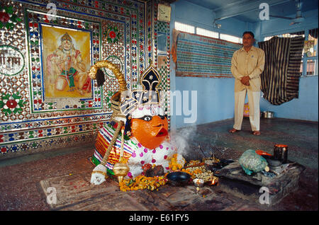 Idole du dieu hindou Hanuman dans un temple. Dans l'arrière-plan, le prêtre du temple (Inde) Banque D'Images