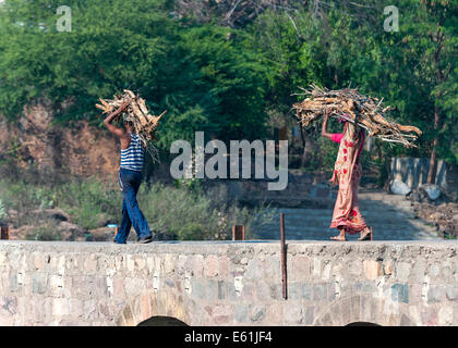 Couple, homme et femme, transporter le bois sur leur tête plus vieux pont de pierre. Banque D'Images