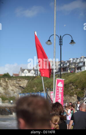 NEWQUAY, CORNWALL, UK - 10 Août : Les restes de l'ouragan Bertha a frappé la côte de Cornouailles provoquant une mer difficile et de hautes vagues. Drapeaux rouges n'arrivent pas à dissuader les internautes d'entrer dans l'océan Banque D'Images