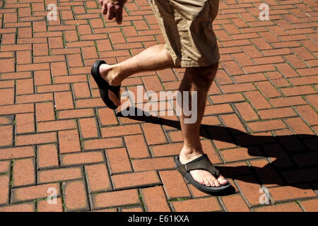 Une personne en short et sandales marcher une brique posée. étage. Banque D'Images