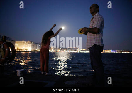 Thessalonique, Grèce. 10e Août, 2014. Les poissons d'un grand-père avec sa petite-fille à Thessalonique port comme la super lune se lève à Thessalonique, Grèce le 10 août 2014. Credit : Konstantinos Tsakalidis/Alamy Live News Banque D'Images